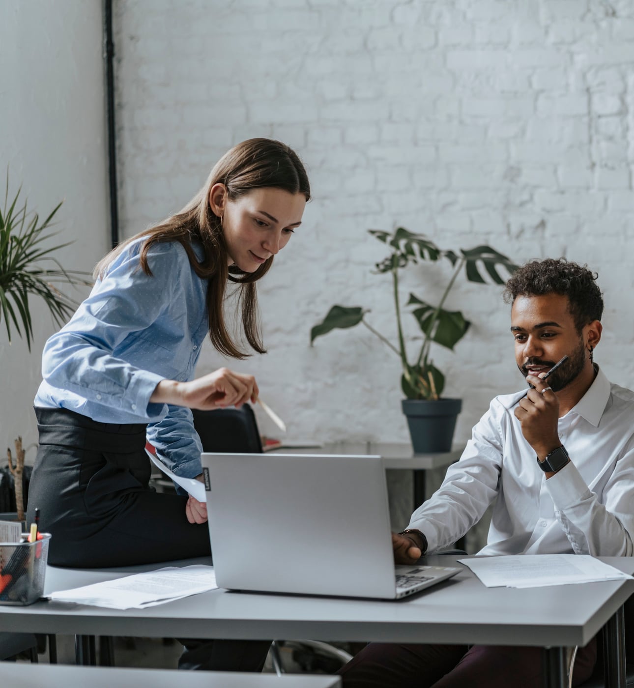 Two colleagues reviewing work together at a laptop